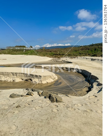 Sandy coastal landscape with shallow stream carving curved channel through beach near Atlantic shoreline along Camino de Santiago. Tourism marketing, coastal geography, environmental education 136363764