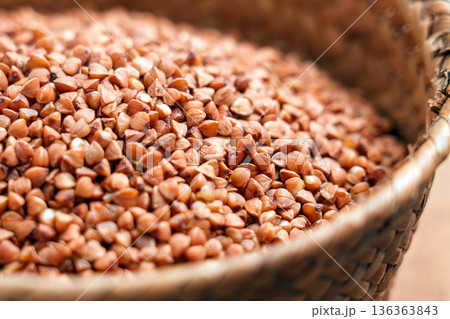 Raw buckwheat groats in woven basket. Natural gluten free cereal ingredient in close up. Raw buckwheat groats in woven basket. Natural gluten free cereal ingredient in close up. 136363843