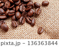 Cracked roasted coffee beans scattered on coarse textured burlap fabric. Aromatic caffeine beverage concept. 136363844