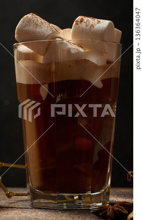 A glass of hot chocolate or cocoa with lots of cinnamon-dusted marshmallows on a dark background. A cozy winter drink. A glass of hot chocolate or cocoa with lots of cinnamon-dusted marshmallows on a dark background. A cozy winter drink. 136364047