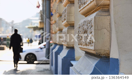 Urban scene with blurred pedestrian walking past building facade detail Urban scene with blurred pedestrian walking past building facade detail 136364549