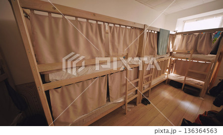 Hostel dormitory with bunk beds and privacy curtains, offering shared accommodation 136364563