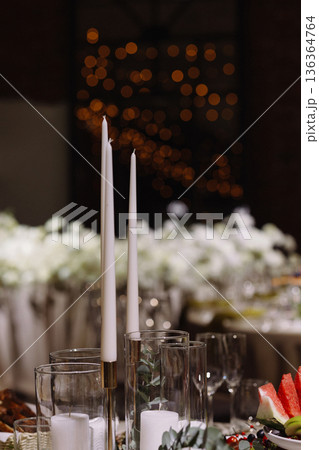 Festive dining table with candles and food in brick hall with dark background 136364764