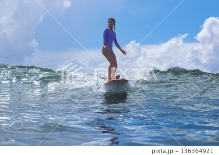 Female Surfer On Longboard Under Tropical Blue Sky By Peaceful Horizon Female Surfer On Longboard Under Tropical Blue Sky By Peaceful Horizon 136364921