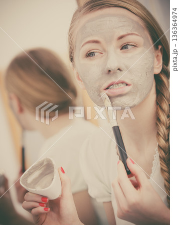 Woman with grey clay mud mask on her face 136364974