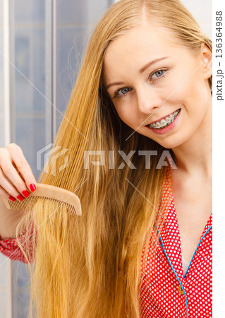 Woman combing her long hair in bathroom 136364988