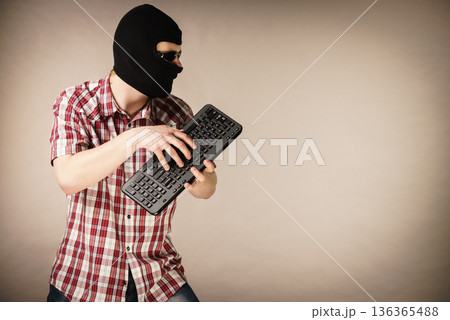 Man wearing balaclava holding keyboard Man wearing balaclava holding keyboard 136365488