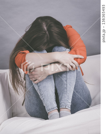 Worried woman sitting on sofa 136365493