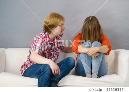 Woman confiding to man on sofa 136365524
