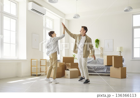 Happy couple moving into new apartment, giving high five to celebrate relocation 136366113
