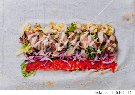 Open pork shawarma wrap with tomatoes, pickled onions and sauce, top view Open pork shawarma wrap with tomatoes, pickled onions and sauce, top view 136366114