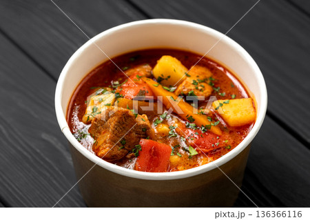 Hungarian bograch goulash soup with beef and vegetables in kraft bowl on dark wooden table Hungarian bograch goulash soup with beef and vegetables in kraft bowl on dark wooden table 136366116