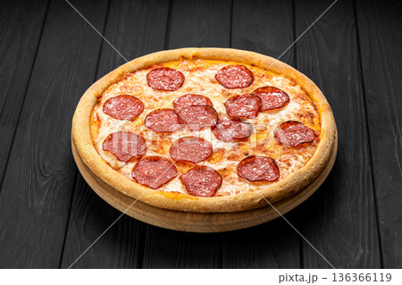 Pepperoni pizza on wooden board over dark rustic table, top view 136366119