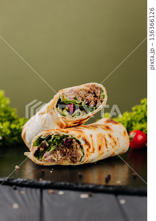 Grilled tuna tortilla wraps with greens, sauce and tomatoes on slate 136366126