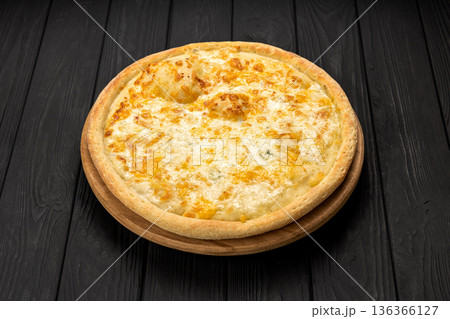Quattro formaggi cheese pizza on wooden board, dark rustic background 136366127
