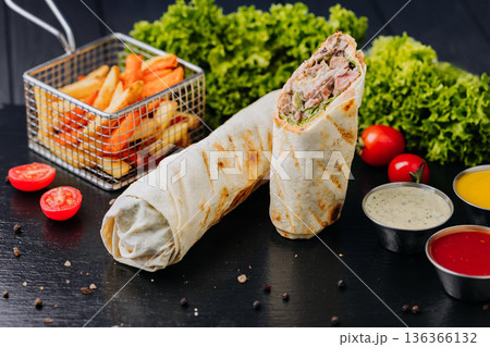 Pork shawarma wraps with fries and ketchup sauce on black table, close up Pork shawarma wraps with fries and ketchup sauce on black table, close up 136366132