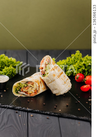 Grilled salmon tortilla wraps with avocado sauce and fresh greens on black slate 136366133