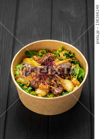 Warm liver salad with caramelized pear, mixed greens and crispy onions in kraft bowl 136366140