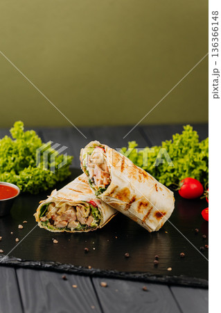 Grilled chicken tortilla wraps with greens and sauce on black slate Grilled chicken tortilla wraps with greens and sauce on black slate 136366148