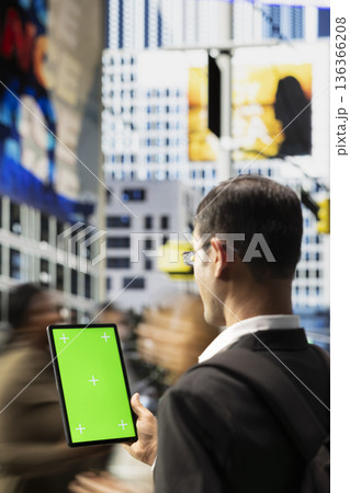 Vertical green screen on tablet with indian adult near busy crosswalk with urban people highlighting different lifestyles, multicultural crowd and everyday street activity in a metropolitan area. 136366208