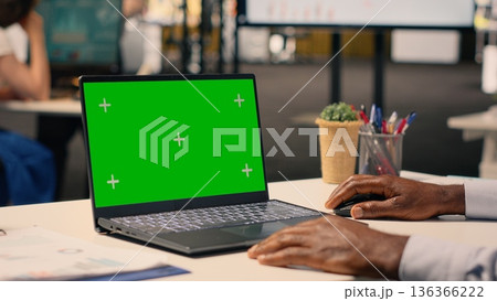 Green screen mockup with black man sitting at business office desk, corporate lifestyle image of daily tasks. Forecasting reports and analytics dashboard support strategic planning and goals. 136366222