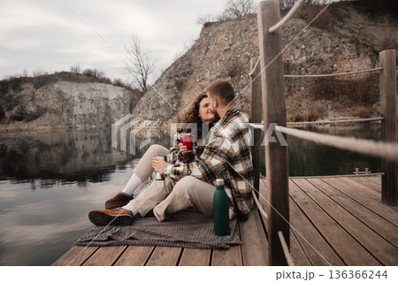 Couple enjoys warm drinks on a dock by a lake on Valentines Day in early spring Couple enjoys warm drinks on a dock by a lake on Valentines Day in early spring 136366244