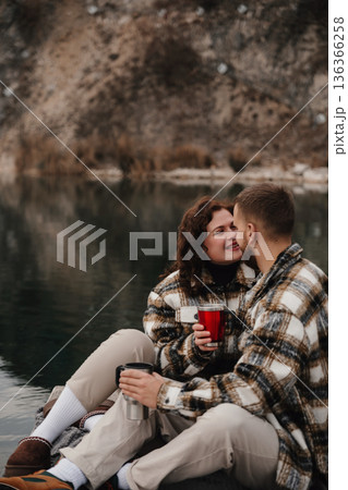 Couple enjoys time by the water on Valentines Day while holding warm drinks and sharing a moment together Couple enjoys time by the water on Valentines Day while holding warm drinks and sharing a moment together 136366258