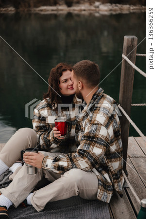 Couple enjoying a cozy moment together by the water on Valentines Day while sharing drinks Couple enjoying a cozy moment together by the water on Valentines Day while sharing drinks 136366259