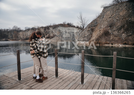 Couple embraces on wooden dock by the water during Valentines Day in winter month 136366265