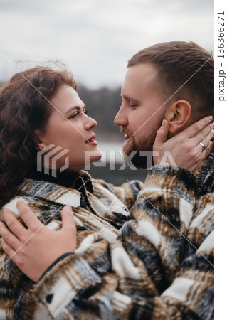 Couple shares a romantic moment during a winter stroll on Valentines Day by the lake 136366271