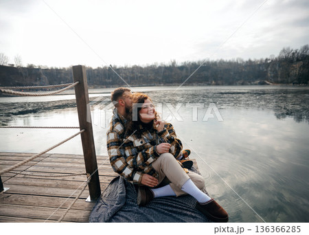 Couple enjoys quiet moment by the lake on Valentines Day while sitting together on a blanket 136366285