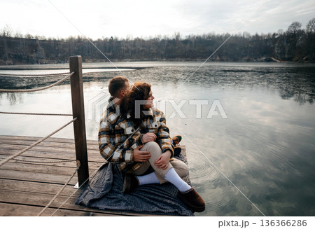 Couple enjoys a quiet moment by the water on Valentines Day, sharing their love at sunset in a cozy outdoor setting Couple enjoys a quiet moment by the water on Valentines Day, sharing their love at sunset in a cozy outdoor setting 136366286