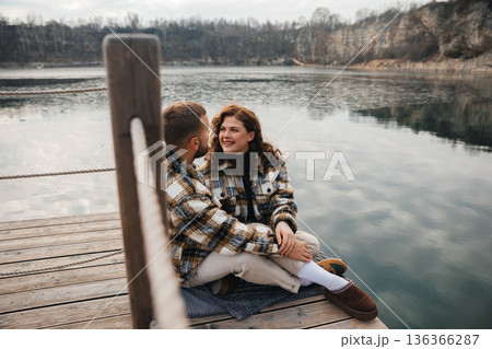 Couple enjoys a moment by the water on a wooden dock during Valentines Day Couple enjoys a moment by the water on a wooden dock during Valentines Day 136366287