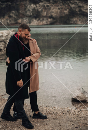 Couple enjoying a walk by the water on Valentines Day in a natural setting surrounded by rocks and water 136366303