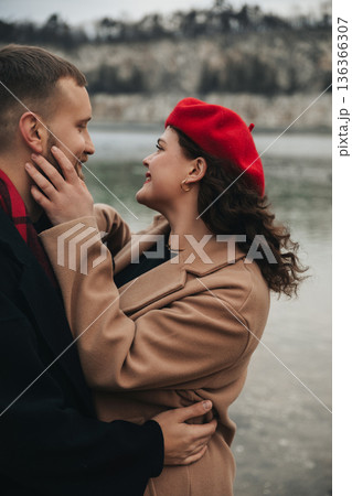 Couple enjoys a romantic moment by the water on Valentines Day wearing warm clothes and sharing smiles in nature Couple enjoys a romantic moment by the water on Valentines Day wearing warm clothes and sharing smiles in nature 136366307