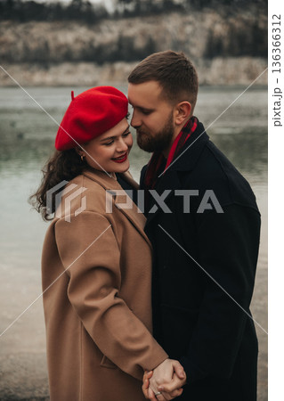 Couple enjoying a romantic moment together by the lake on Valentines Day with a cozy outfit in winter 136366312