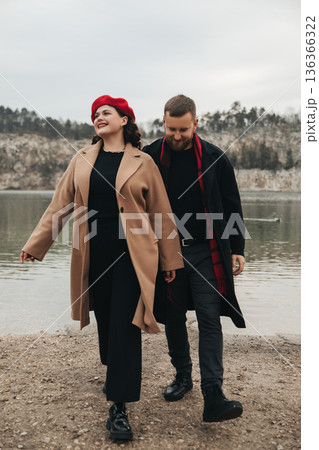 Couple walks along a lakeside path on a cloudy day enjoying time together in nature 136366322