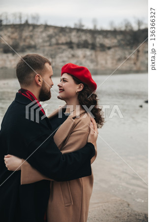 Couple enjoys romantic moment by the water on Valentines Day while sharing a warm embrace and smiles 136366327