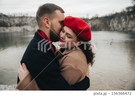 Couple sharing a moment by the lake on Valentines Day with a soft embrace and warm smiles 136366472