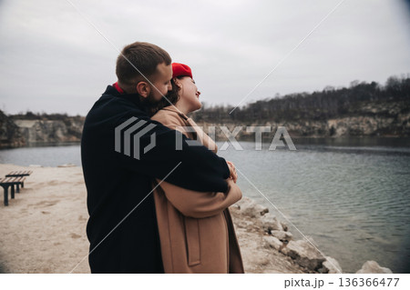 Couple embraces by the lake on a cloudy day during Valentines Day celebration Couple embraces by the lake on a cloudy day during Valentines Day celebration 136366477