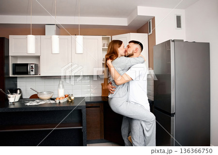 Couple shares a moment in the kitchen, enjoying time together while preparing food in a modern apartment during the morning 136366750