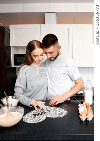 Couple prepares dough together in modern kitchen while enjoying each others company during a weekend morning Couple prepares dough together in modern kitchen while enjoying each others company during a weekend morning 136366773