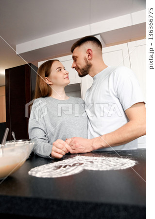 Couple shares a moment in the kitchen while preparing a dessert together during an evening at home in a cozy apartment setting 136366775