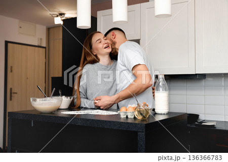 Couple enjoys cooking together in the kitchen while sharing smiles and laughter during a morning breakfast preparation at home Couple enjoys cooking together in the kitchen while sharing smiles and laughter during a morning breakfast preparation at home 136366783