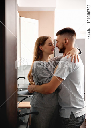Couple enjoys a moment together in the kitchen while preparing dinner in the evening at their home 136366796