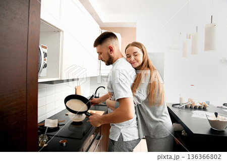 Couple cooking breakfast together in a modern kitchen during the morning hours Couple cooking breakfast together in a modern kitchen during the morning hours 136366802