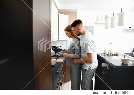 Couple cooking together in a modern kitchen during a weekend morning while sharing a warm moment of connection and love 136366806