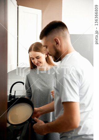 Couple cooking together in kitchen while preparing food and enjoying each others company in a modern home environment Couple cooking together in kitchen while preparing food and enjoying each others company in a modern home environment 136366809