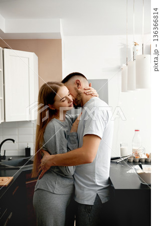 Couple embraces in their kitchen after cooking together, creating a warm moment during the evening Couple embraces in their kitchen after cooking together, creating a warm moment during the evening 136366814