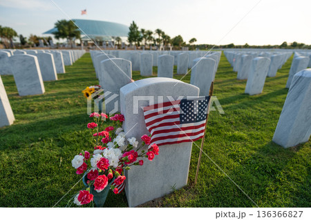 Sarasota National Cemetery with many white headstones with USA flags and flowers on green grass lawn. Memorial Day concept Sarasota National Cemetery with many white headstones with USA flags and flowers on green grass lawn. Memorial Day concept 136366827